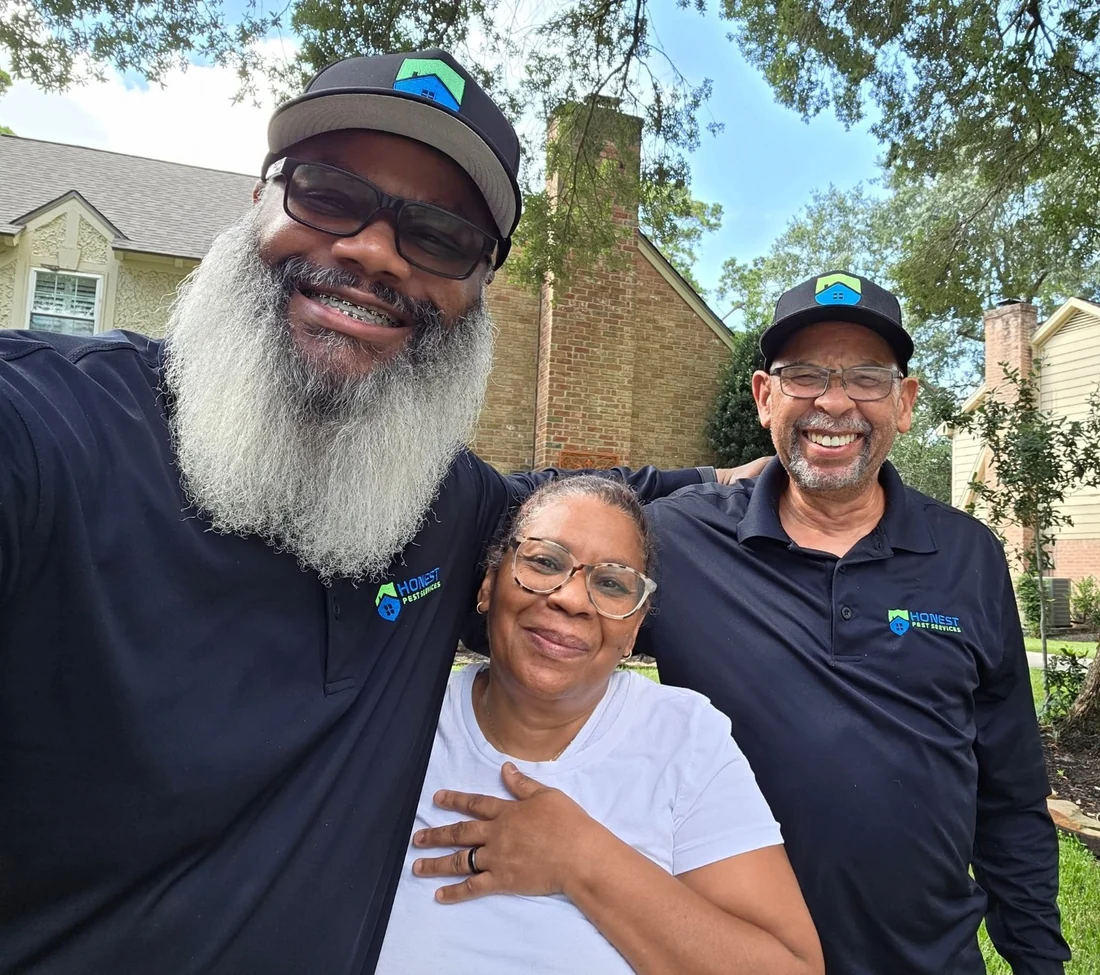 Two Honest Pest Services team members and a woman standing together outside a home