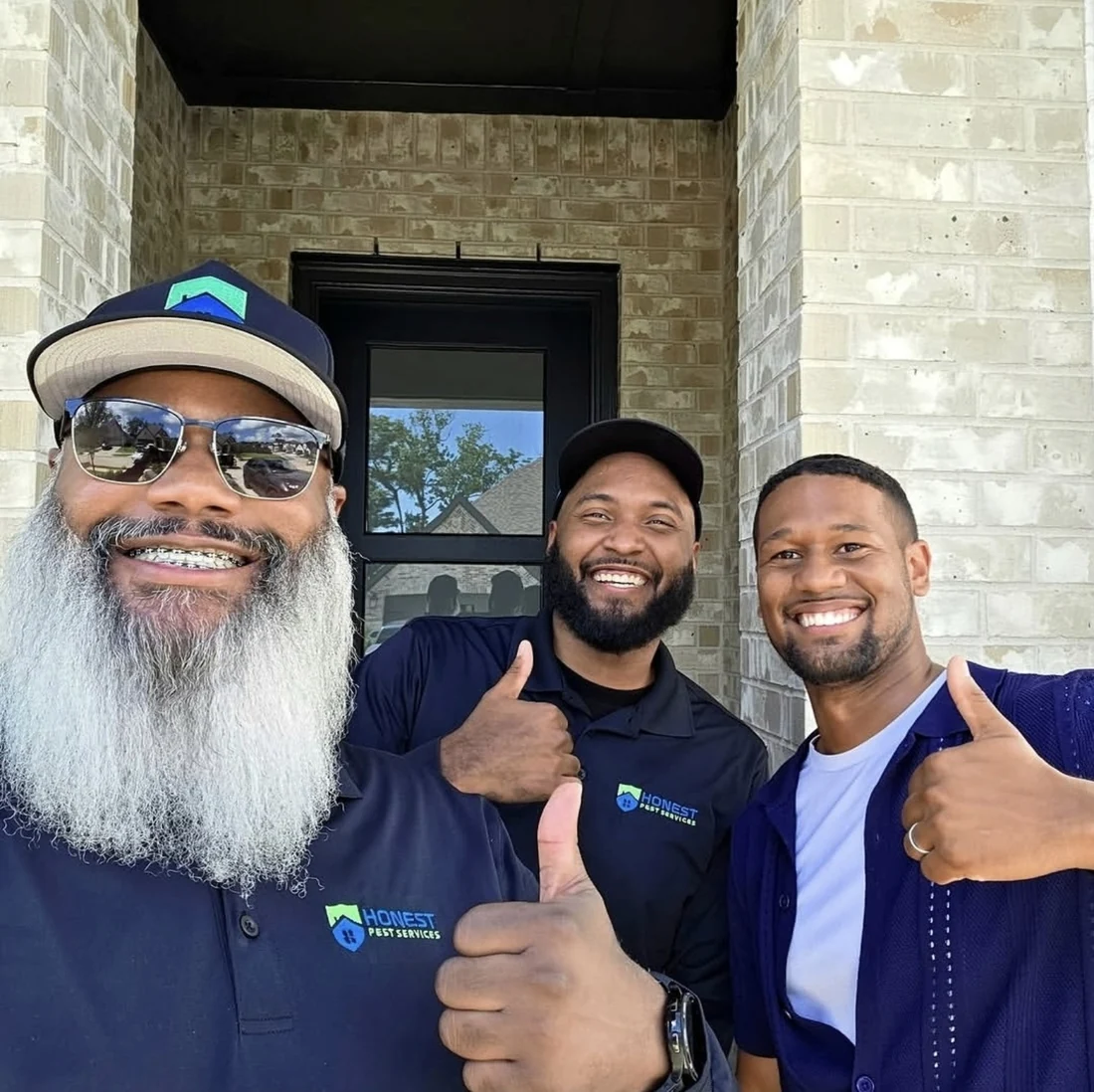 James Wyatt and two men smiling outside a home, with Honest Pest Services shirts visible